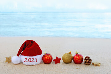 New Year 2024 background with Santa hat and decorations on Caribbean beach.