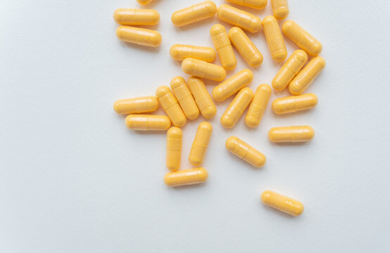 The image shows yellow capsules on a light grey background, suitable for healthcare and pharmaceutical themes.