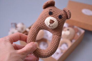 Crochet baby rattle toy bear from brown cotton in a woman's hand as newborn gift idea