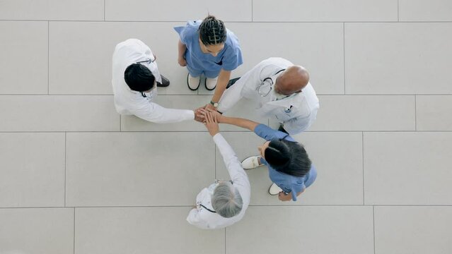 Top view, hands together and doctors with support, healthcare and trust in a hospital, target and collaboration. Group, staff or medical professionals with team building, clinic mission or motivation