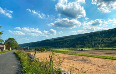 Naklejka premium Panoramic Yorkshire Dales landscape, with ploughed fields, a tractor, farms, and barns near, Starbotton, UK