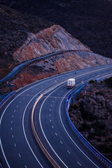 Truck with refrigerated semi-trailer driving on an empty highway, top view.