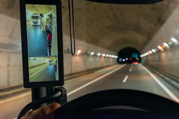 View from inside the cabin of a truck of a tunnel and another truck passing by seen through the...