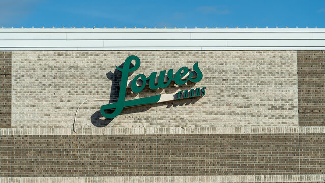 Lowes Foods logo, supermarket chain from North Carolina. The logo is on a brick wall, blue skies in the background.