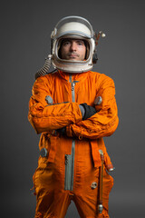 Serious astronaut is standing in the space suit and helmet on the gray background. © Dmitriy