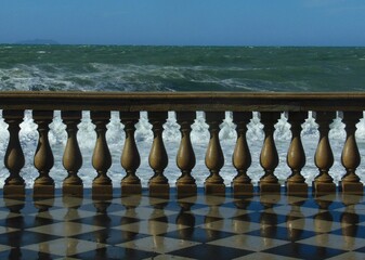 View of the Mediterranean Sea from the Terrazza Mascagni with a wall reflecting on the wet checkerboard floor
