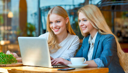 Happy small business owners working with laptop at cafe