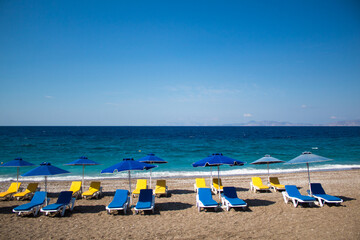Summer vacation concept: empty beach chairs and umbrellas, blue sea in the background. Free copy space