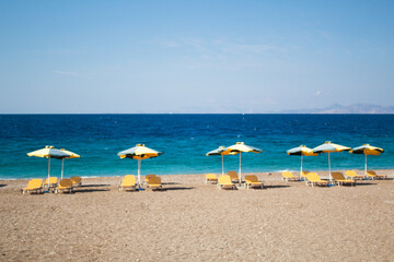 Summer and holiday concept: beach chairs and umbrellas, no people, empty beach, beautiful blue sea
