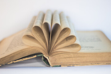 Old, open book arranged in a decorative form, white background, selective focus