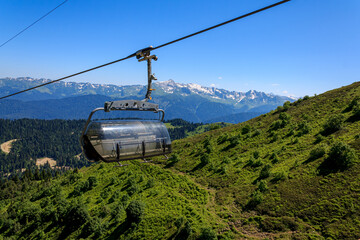 Carousel cable car in the mountains, green mountains on a sunny