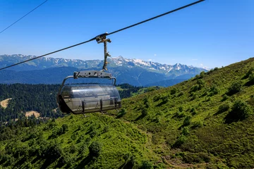 Schilderijen op glas Carousel cable car in the mountains, green mountains on a sunny © daniiD