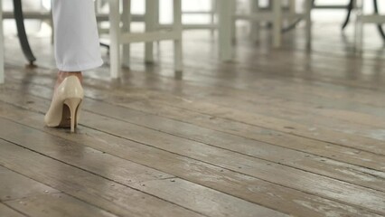 Closeup Beautiful adult female legs in high heels walking on wooden floor