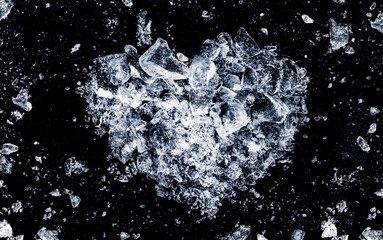 Ice shards crush on a black background in the shape of a heart. Valentine symbol backdrop.
