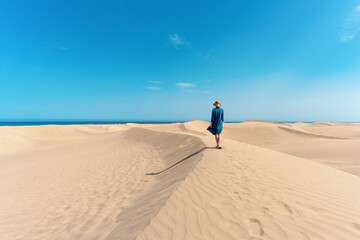 A woman hikes through sand dunes of Maspalomas, Gran Canaria, Spain