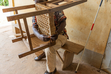 Close-up of chair resting by string tying, on a blind African gentleman legs