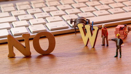 NOW word or concept made by wooden letters on wooden background with white keyboard in the...