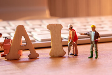 ai word or concept made by wooden letters on wooden background, artificial intelligence abbreviation with white keyboard in the background and miniature workers figurines constructing AI