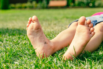 Child's bare feet on green grass in park. Kid foot on green grass on garden. Barefoot concept,...