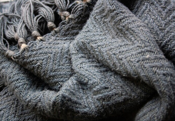 Decorative background of rustic herringbone fabric in grey tones with woollen fringes. 