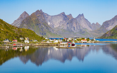 The village of Reine under a sunny, blue sky, with a breathtaking scenery with fjords and sharp...
