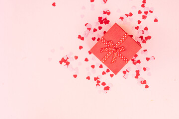 Valentines day festive background with pink hearts and red gift box on pink background
