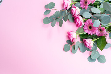 wedding or mothers day background, bouquet of roses and herberas with fresh eucaliptus leaves over plain pink background, copy space