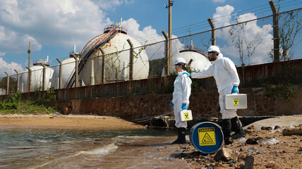 Ecologists in protective suits working  near the coastline and taking samples of water for analysis