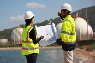 Male and female  chemical engineers hold blueprint works at factories outside