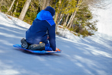 Boy sliding down snowy hill