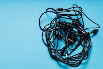 Tangled Black Cables for Modern Gadgets on Blue Background, Copy Space
