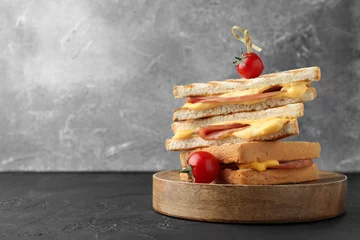 Fotobehang Stack of tasty sandwiches with ham and melted cheese served with tomatoes on black textured table, space for text © New Africa