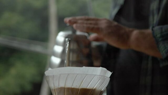 Barista brewing a specialty coffee using a quality coffee extraction method on a camp in Capara&oacute; region of Espirito Santo, state of Brazil