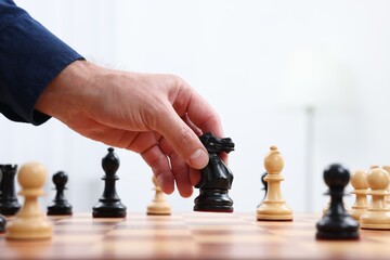 Man moving knight on chessboard against white background, closeup
