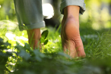 Fototapeta na wymiar Woman walking barefoot on green grass outdoors, closeup