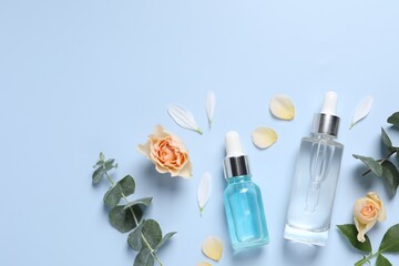 Flat lay composition with cosmetic serums on light blue background, space for text