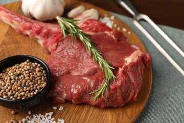 Raw ribeye steak and spices on table, closeup