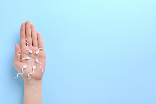 Reproductive medicine. Woman holding figures of sperm cells on light blue background, top view with space for text