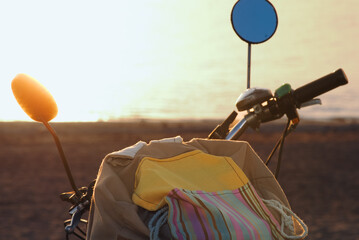 bag and vintage bicycle on the beach at sunset