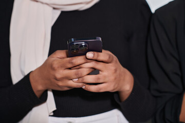 Captured in a close-up moment, a girl in hijab skillfully engages with her smartphone, reflecting a contemporary lifestyle where digital connectivity seamlessly intertwines with cultural expression