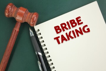 judge's gavel, pen and book with the word bribe taking. the concept of bribery. take a bribe