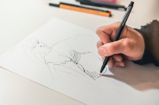 Close-up of a femaile desinger drawing with a pencil.