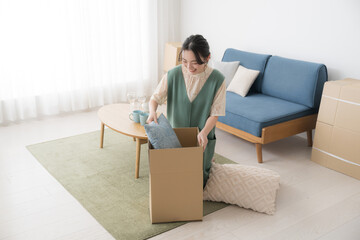 A smiling young woman packing cardboard boxes in preparation for a move.　