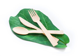 Set of table ware with fork knife and spoon on green fig leaf. Bamboo wood biodegradable recycled materials isolated on white.