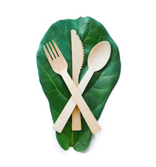 Set of table ware with fork knife and spoon on green fig leaf. Bamboo wood biodegradable recycled materials isolated on white.