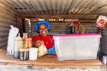 street vendor in a shack, selling to a young african woman, some hot french fries
