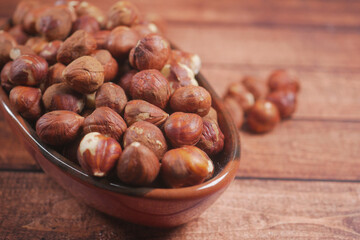 hazelnuts in a container on wooden background,