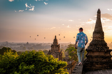 Bagan Myanmar, young men looking at the sunrise on top of an old pagoda temple. a European man on...