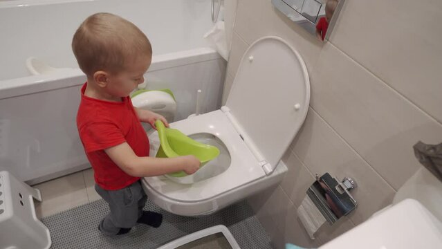 Toddler child learns to pour the contents of potty down the toilet