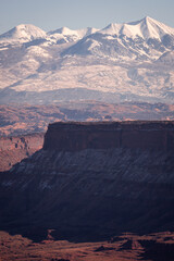 southern utah snow covered mountains towering over red rock formations by Moab